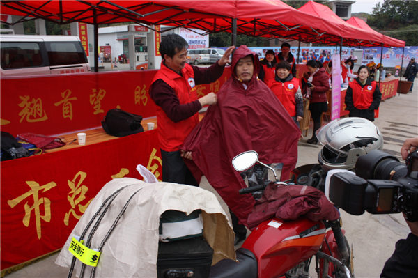 梧州市總工會(huì)的黨員義工們?cè)谑袞|出口春運(yùn)服務(wù)站助力&ldquo;摩托大軍&rdquo;平安返鄉(xiāng)，幫助他們檢查車輛和行李，穿上雨衣。--黃賀峰攝.j